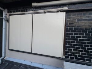 尼崎市で鉄部塗装工事の一環として雨戸の仕上げ塗装を行っている様子