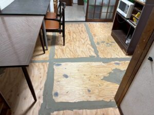 尼崎市 床リフォームで合板の継ぎ目とビス穴をパテ処理している様子