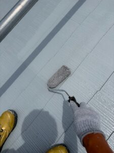 尼崎市でスレート屋根をローラーで塗装している様子