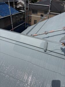 尼崎市でスレート屋根をローラーで塗装している様子