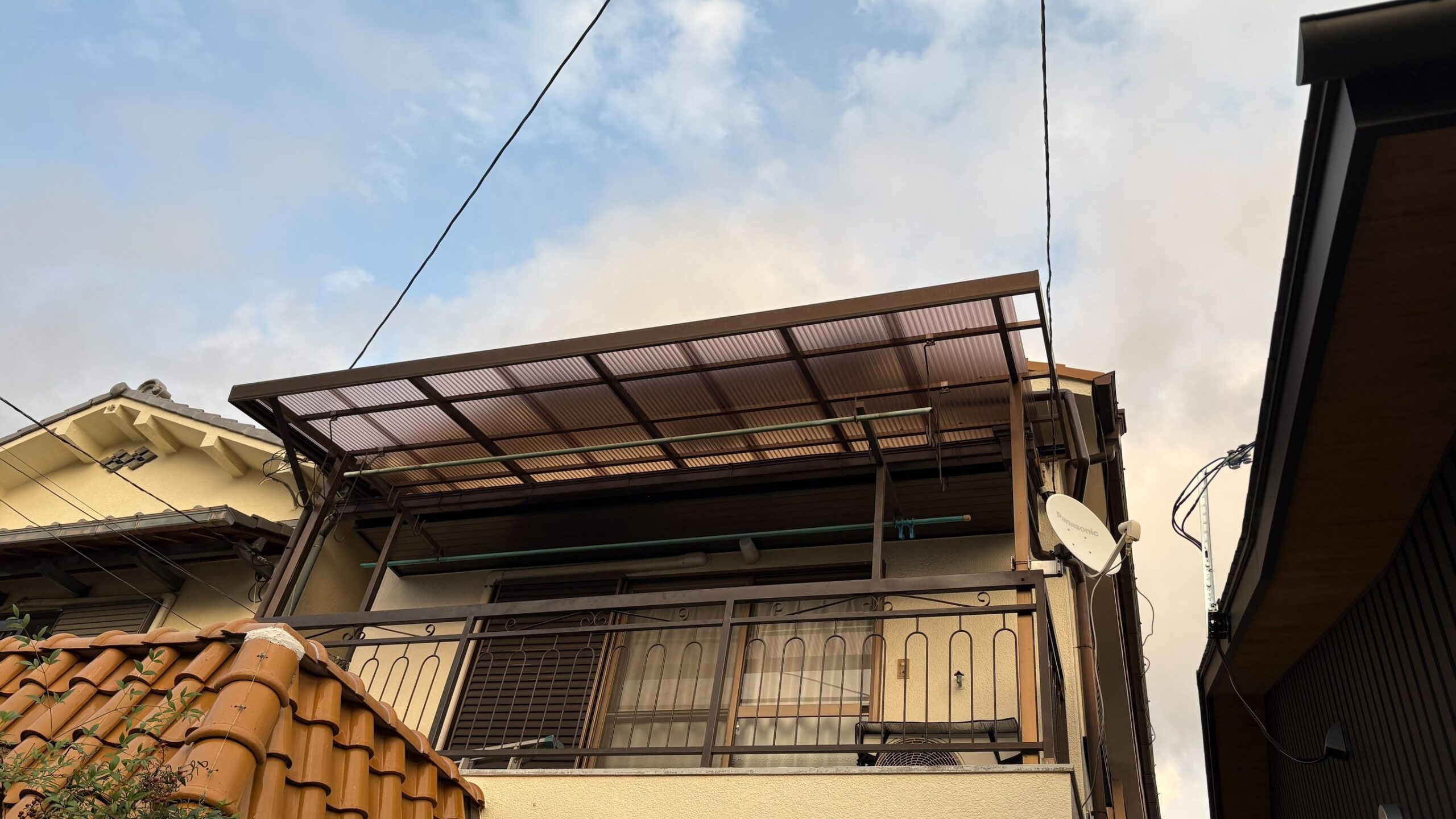 住宅2階のベランダ屋根で波板を張り替えている施工中の全景
