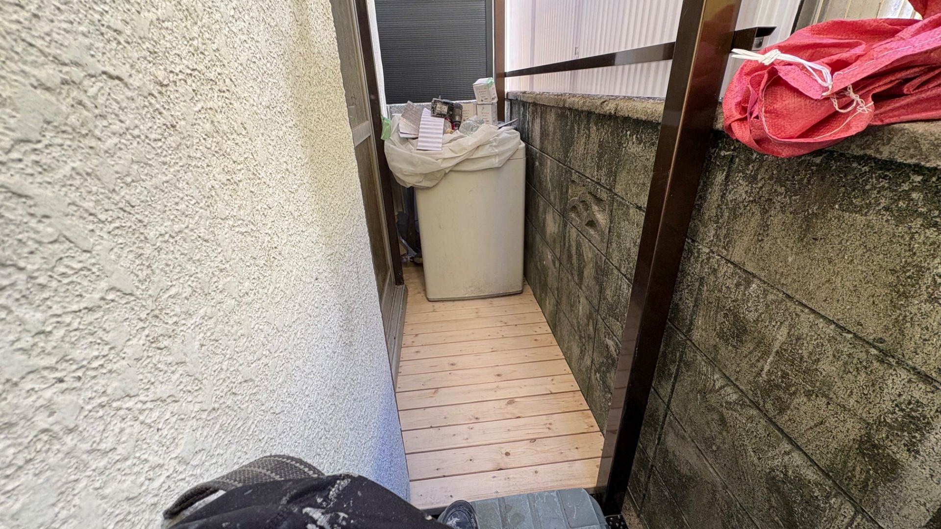 住宅の裏庭の細長い通路に木製床板を設置した床上げ工事の様子